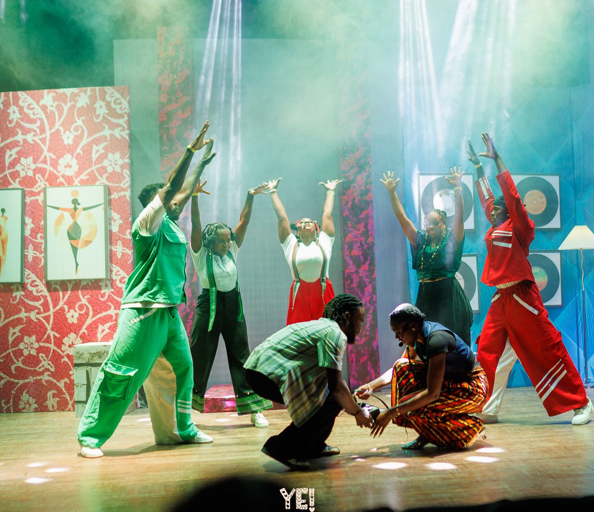 YE! dancers reach up as two performers kneel centre stage
