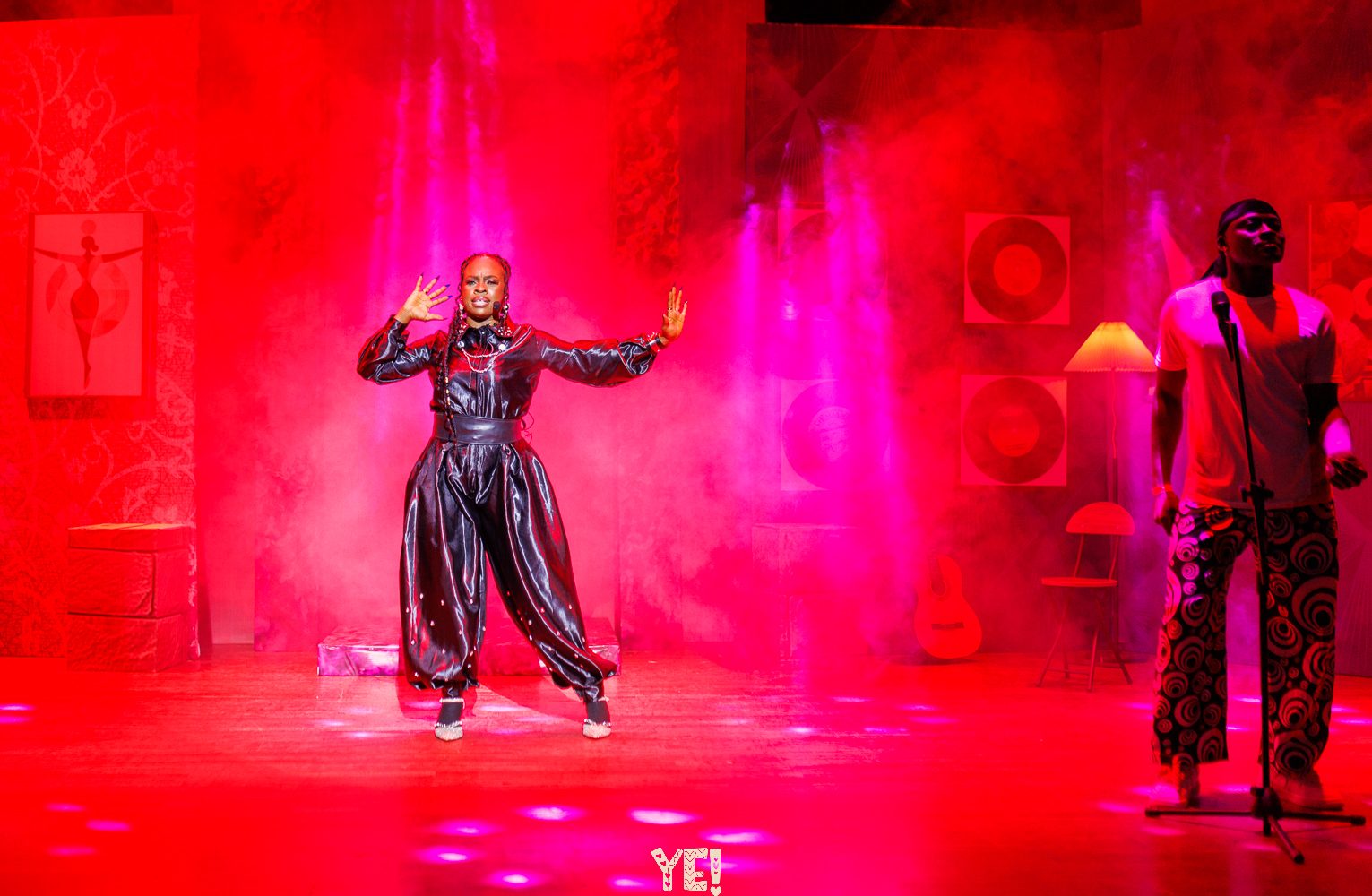 A YE! performer in a black satin suit under red light