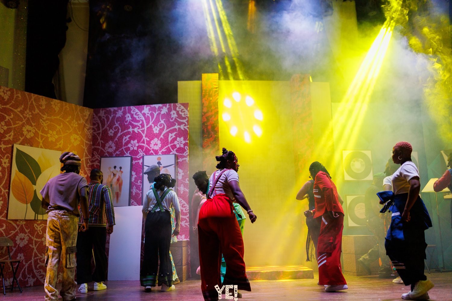 The YE! company dances under yellow stage beams